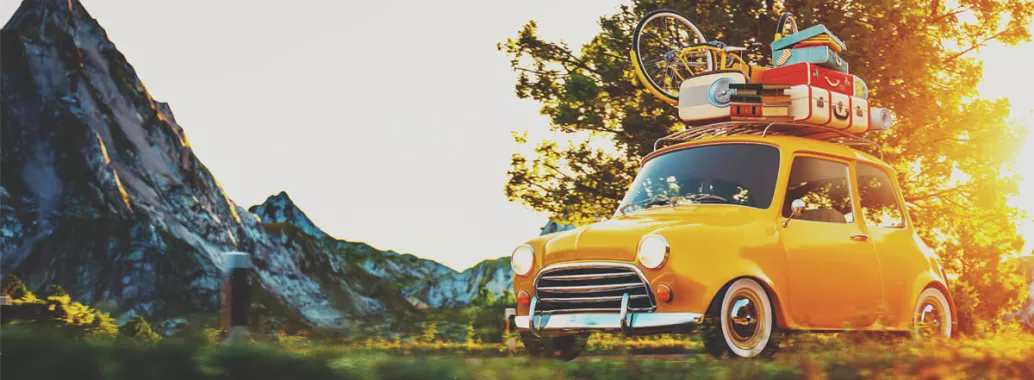 Voiture jaune avec bagages sur le toit roulant sur une route avec montagne au loin